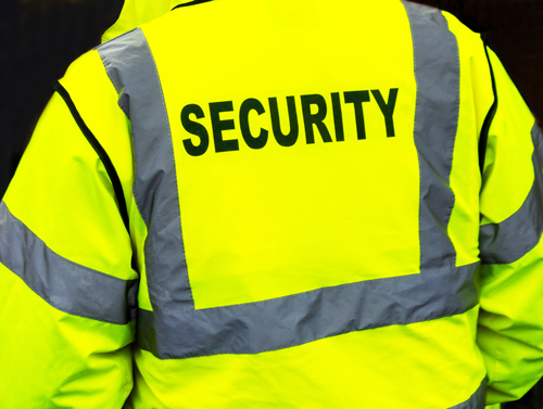 person wearing a bright yellow security jacket with the word security printed on the back in bold letters ensuring safety in a secure environment
