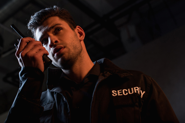 security guard speaking into radio communication in a dimly lit environment representing protection and safety